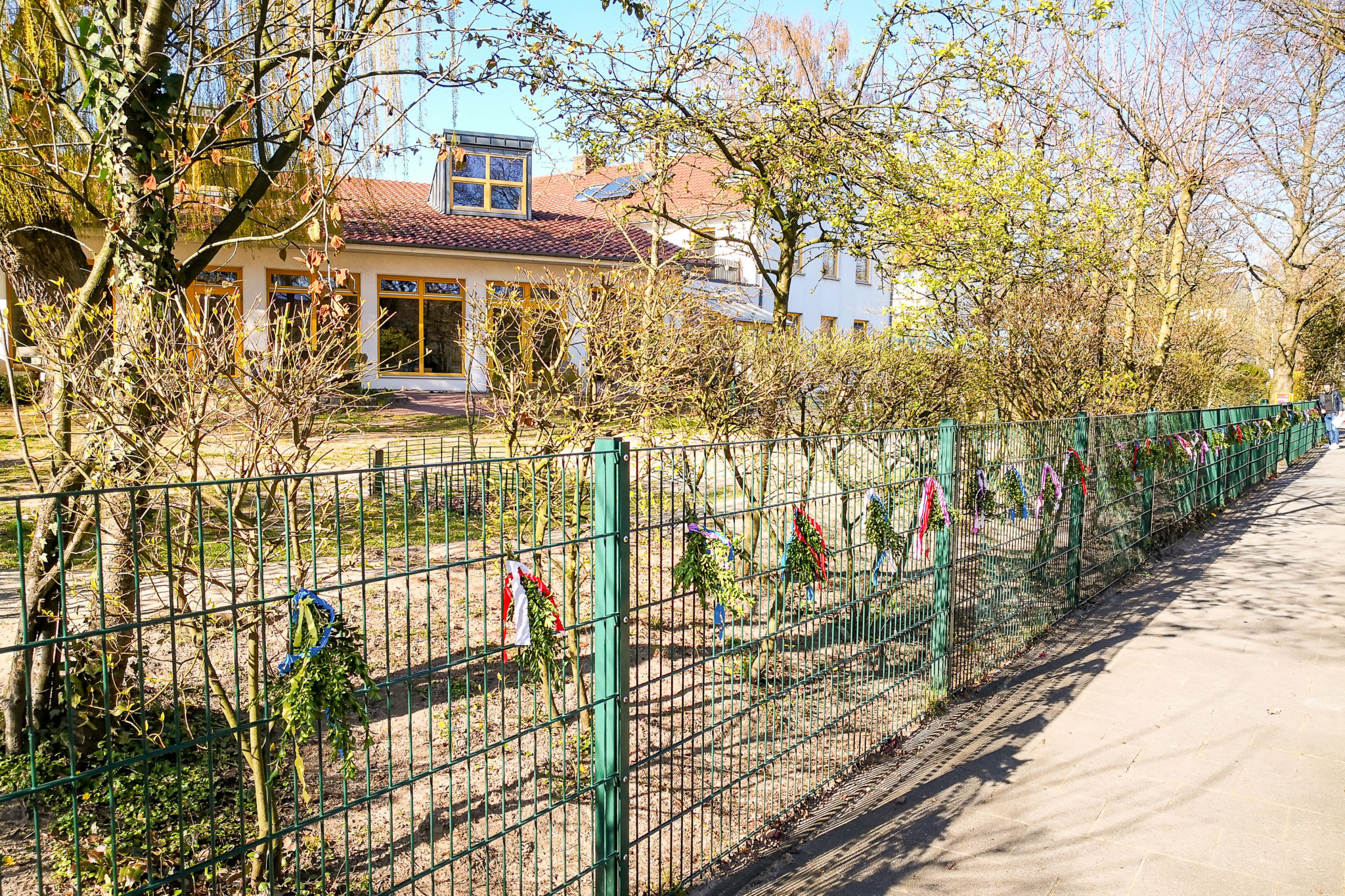 Wir haben uns überlegt, den Zaun trotzdem mit Buchsbaumzweigen zu schmücken um an den Einzug in Jerusalem zu erinnern. Sie alle sind eingeladen, in der Karwoche, auf einem Ihrer Spaziergänge, einen geschmückten Buchsbaumzweig vom Zaun zunehmen. Nehmen Sie ihn als Symbol der Vorbereitung auf Ostern und als kleinen Gruß der Mitarbeiterinnen an Sie und Ihre Kinder.
